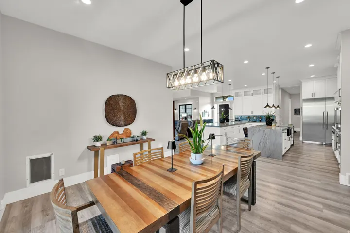 Open-concept living space featuring wood-finish flooring, recessed lighting, and a linear chandelier