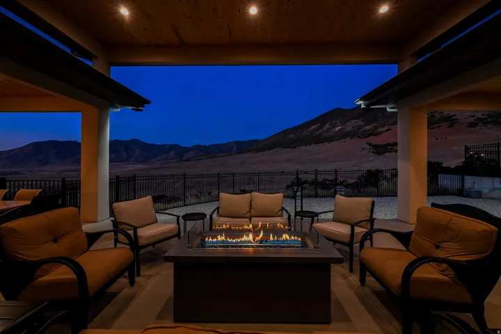 Covered patio with recessed lighting, integrated fire pit, and mountain backdrop