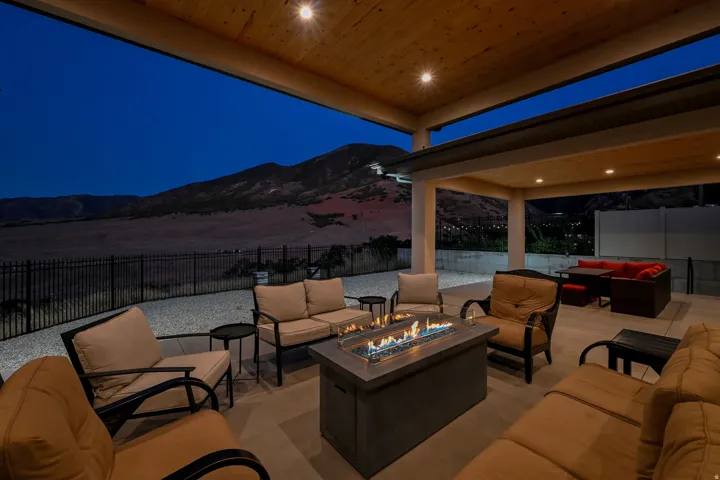 Covered patio featuring a gas fire pit, recessed lighting, wood-finish ceiling, mountain backdrop, and a perimeter fence