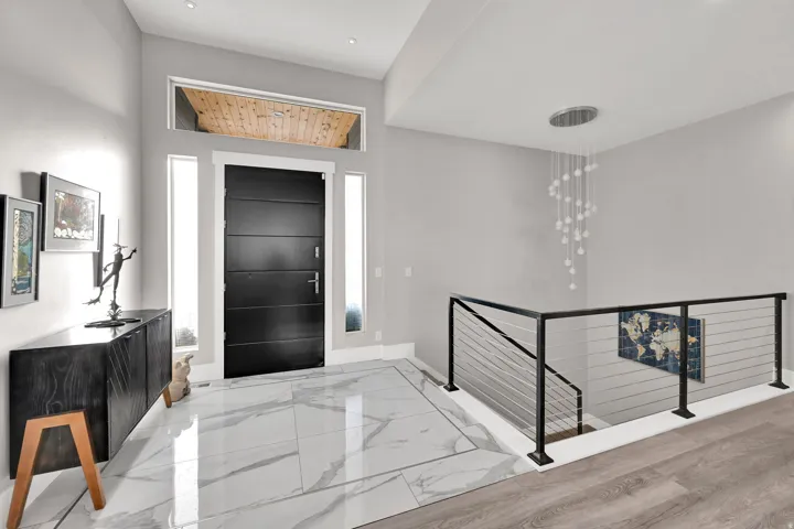 Spacious entryway featuring large format tile flooring, a modern black entry door with transom window, and a contemporary cable railing system