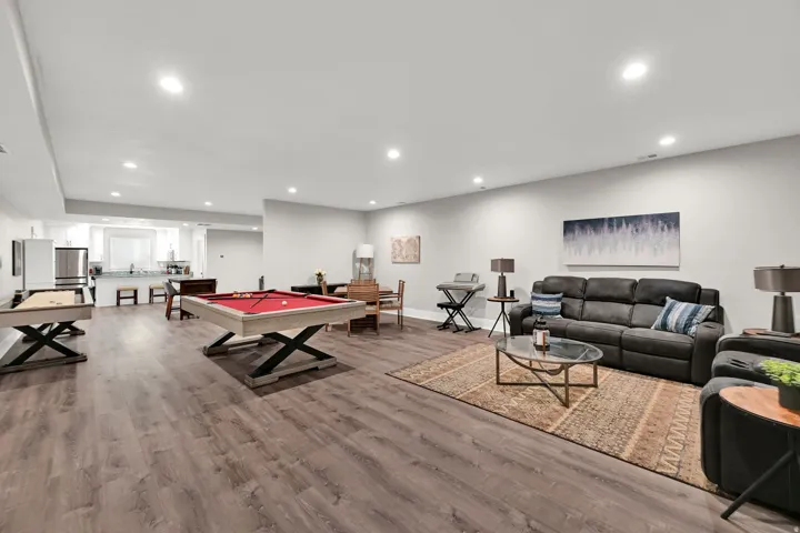 Spacious entertainment area with recessed lighting, wood-finish flooring, and a dedicated kitchen