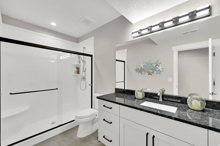 Spacious shower with black-framed glass enclosure, built-in bench, and shelving