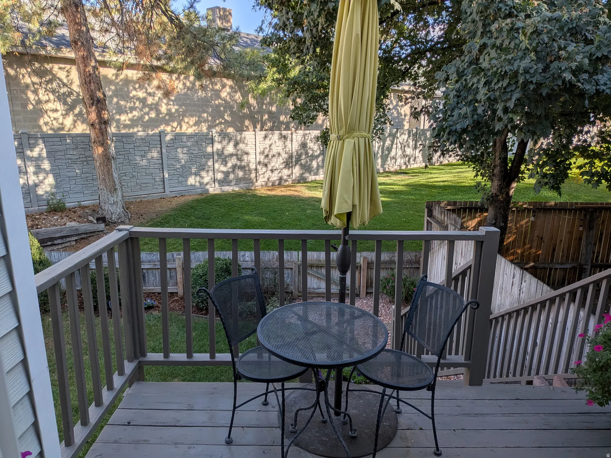 Wooden deck with railing leading to a graded lawn