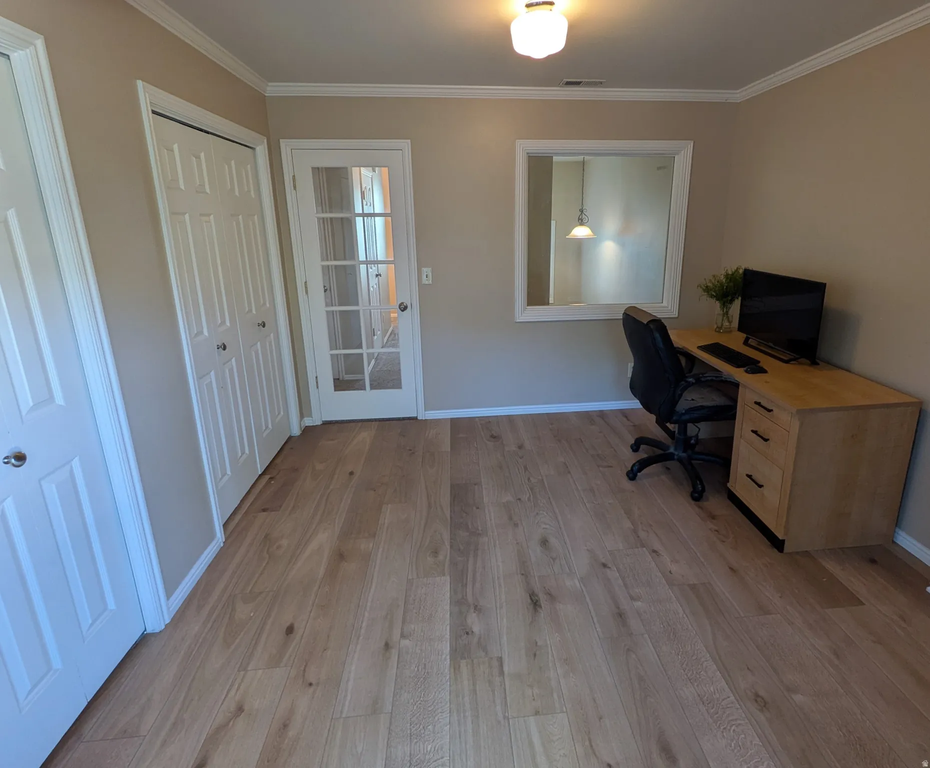 Light wood-finish flooring, crown molding, and a paneled door