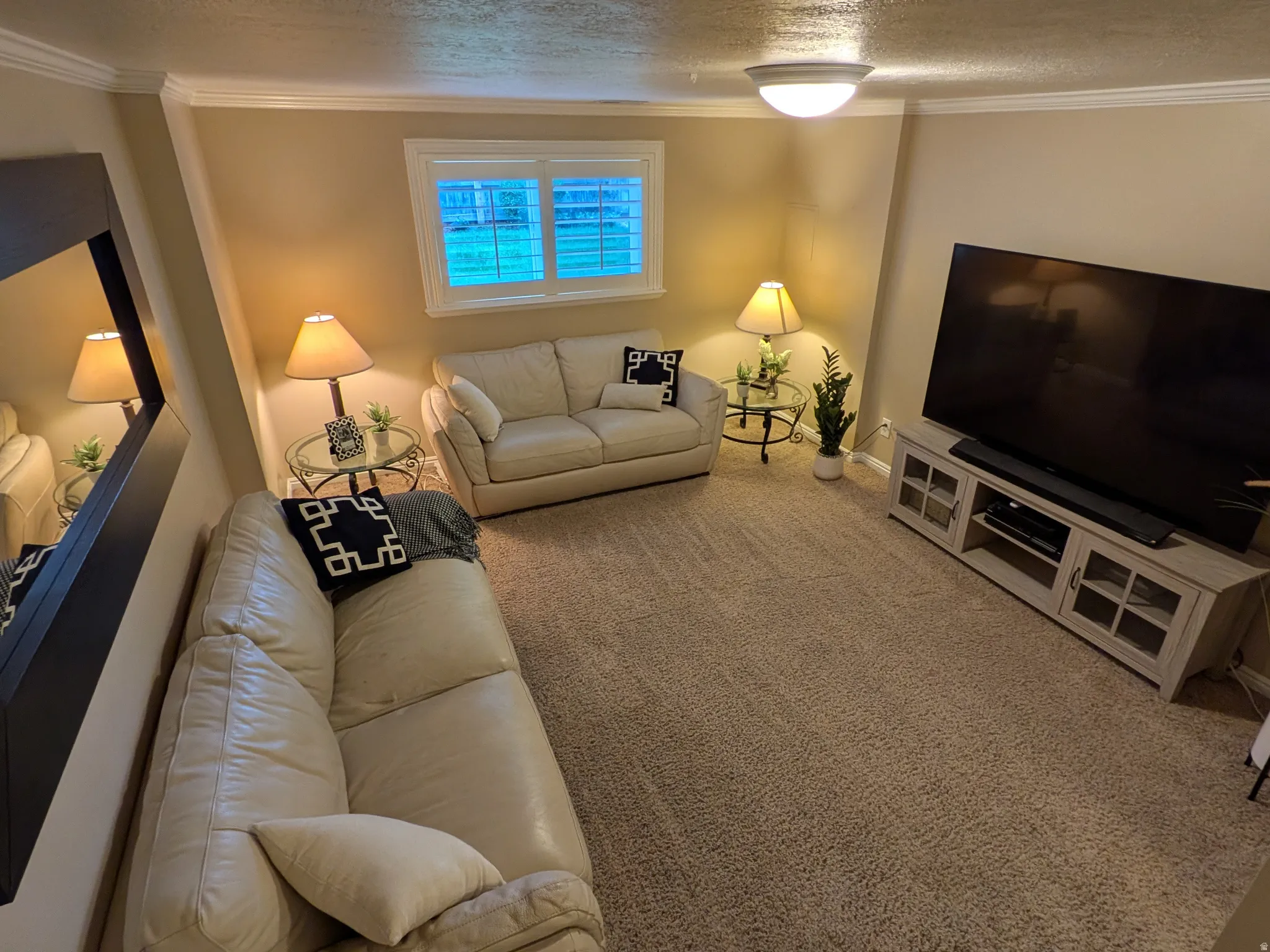 Carpeted living area with crown molding, a window with plantation shutters
