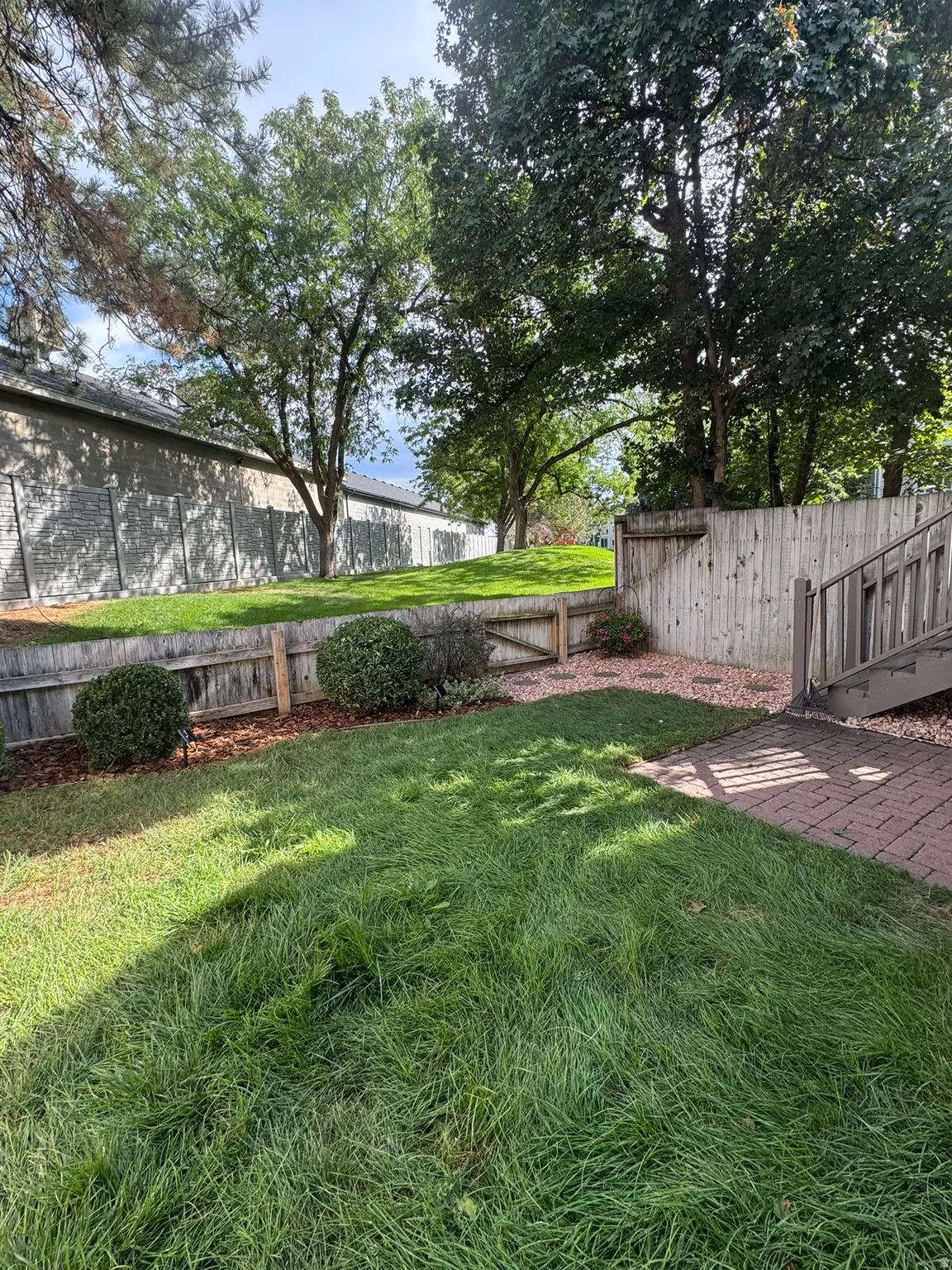 Grassed backyard, wood fencing, and a brick paver patio