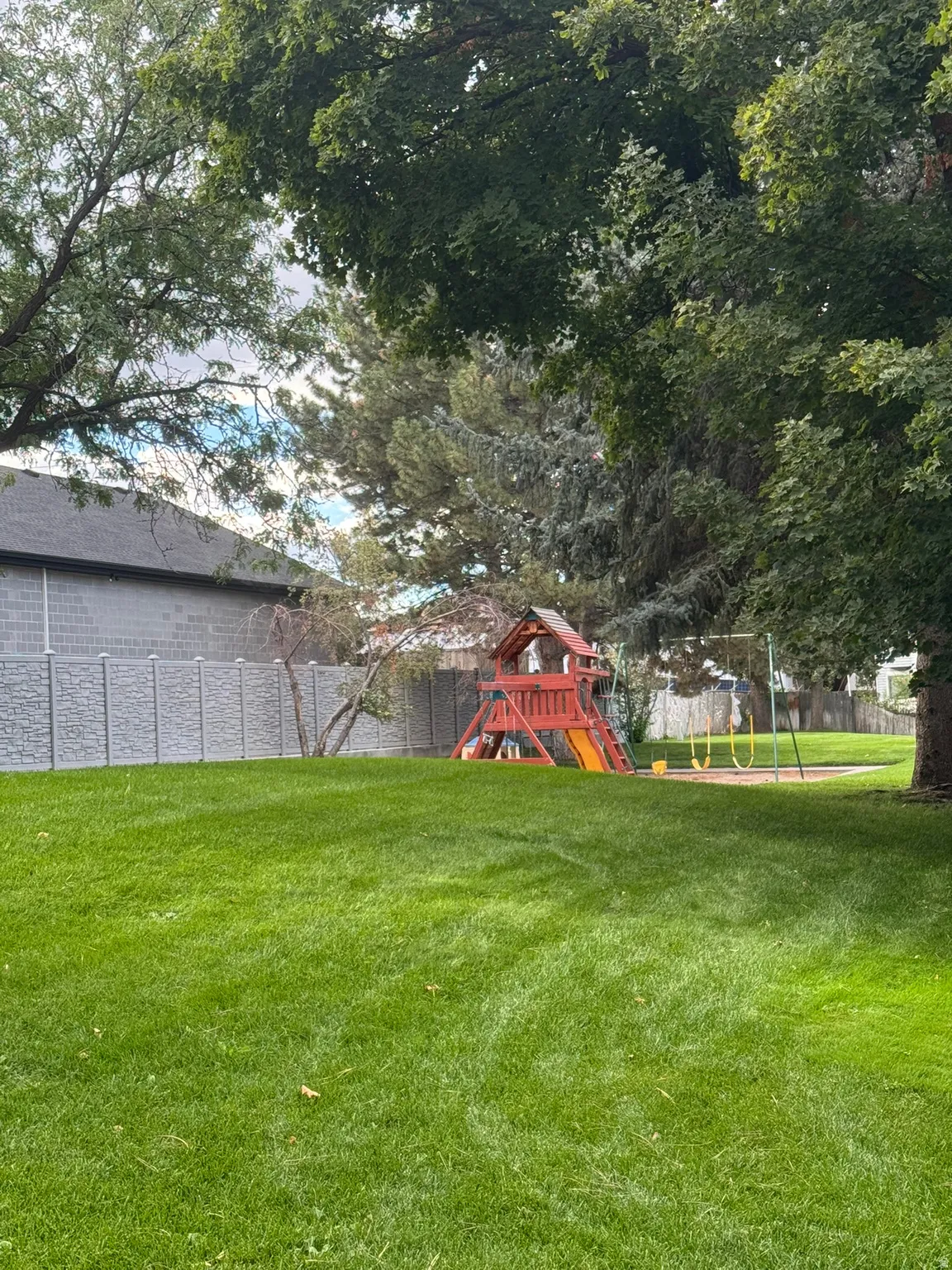 Expansive lawn with mature trees and a privacy fence
