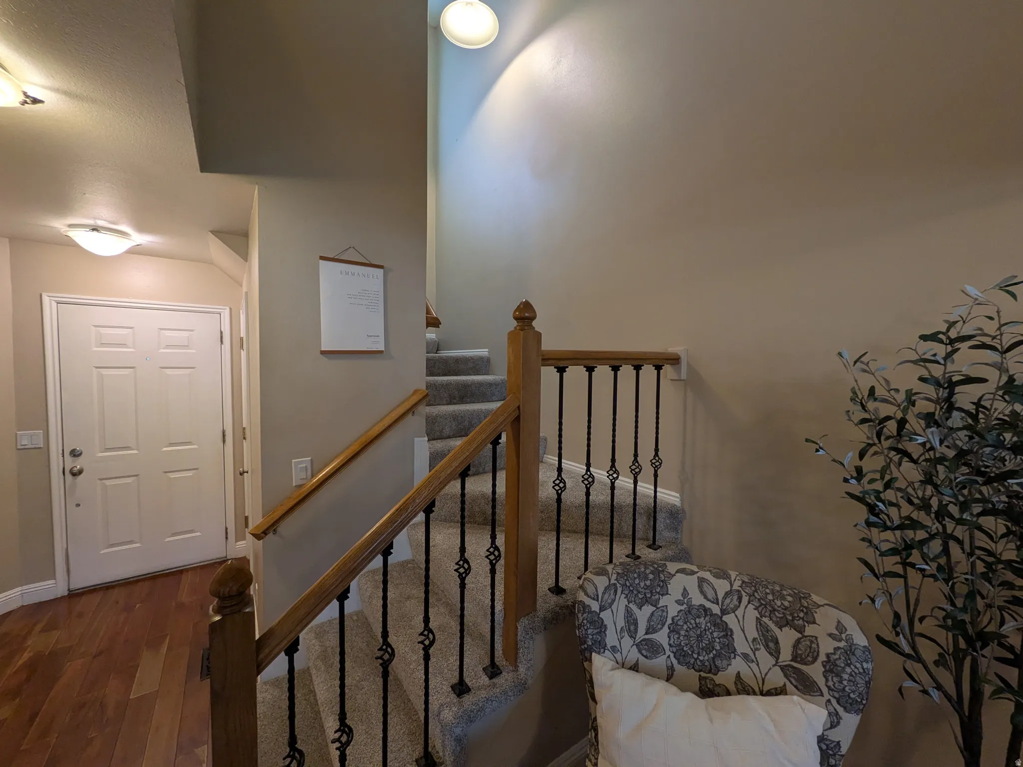 Carpeted staircase, wood banister with wrought iron balusters, and flush mount lighting
