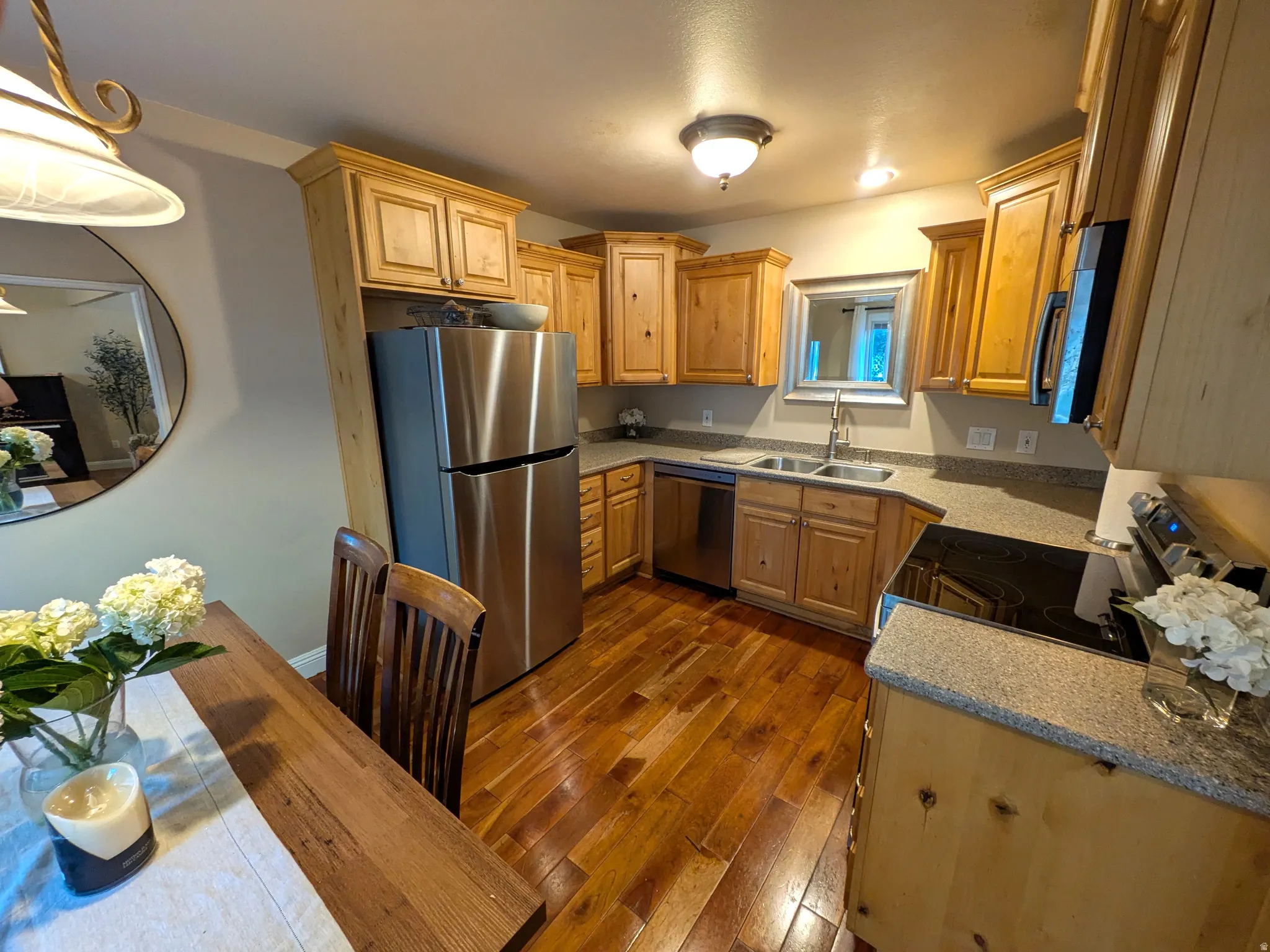 Kitchen featuring hardwood flooring, natural wood cabinetry, stainless steel appliances, and granite-style countertops