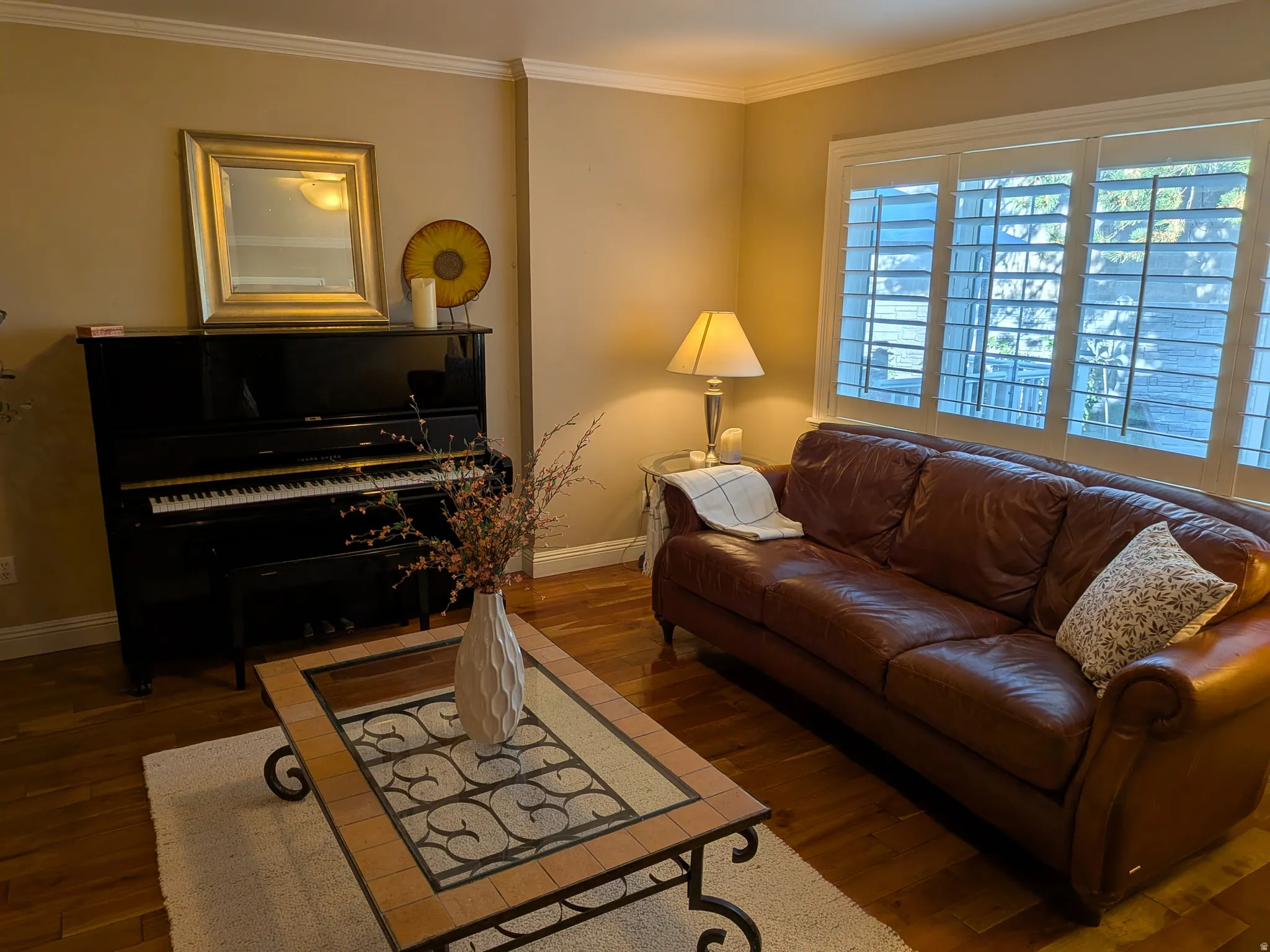 Warm interior featuring hardwood flooring, crown molding, and plantation shutters