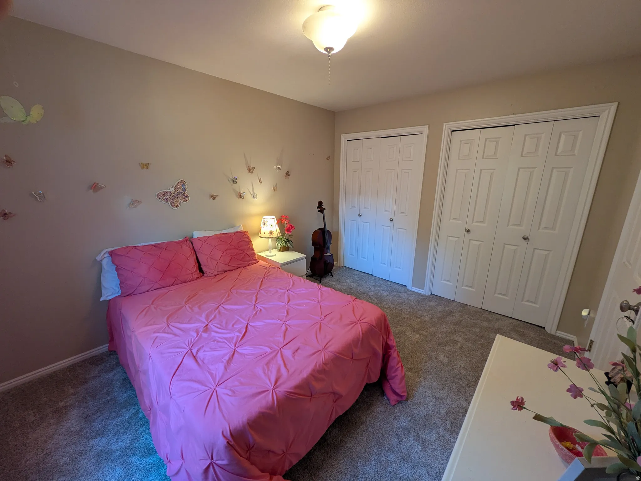 Plush carpeting throughout, neutral wall tones, two white bi-fold closet doors, and an overhead flush-mount light fixture