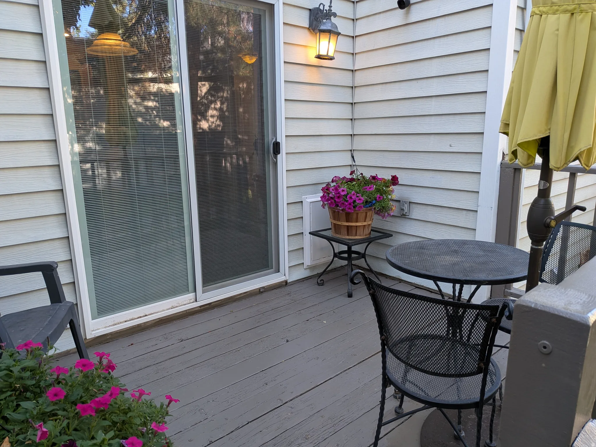 Outdoor deck with light-colored siding, a sliding glass door, and an exterior wall light fixture