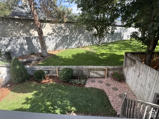 Backyard featuring a manicured lawn, established trees, wood fencing, and a decorative gravel pathway with stepping stones