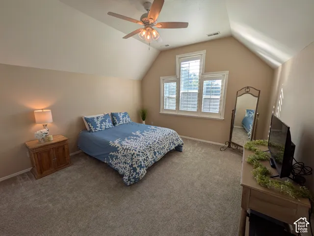 Vaulted ceiling, carpeted flooring, ceiling fan, multiple windows with blinds, and neutral wall tones