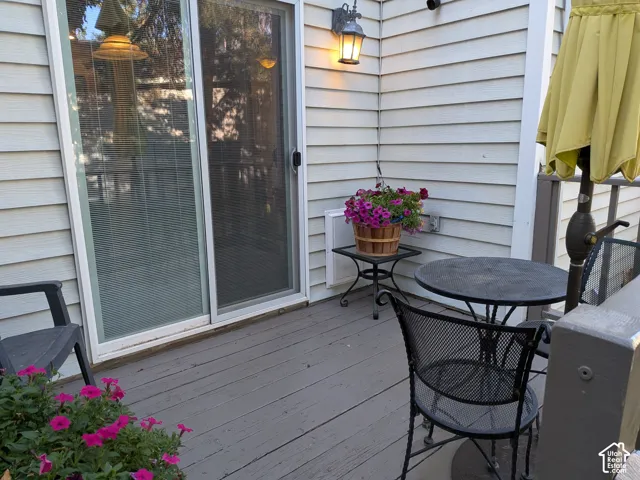 Outdoor deck with light-colored siding, a sliding glass door, and an exterior wall light fixture