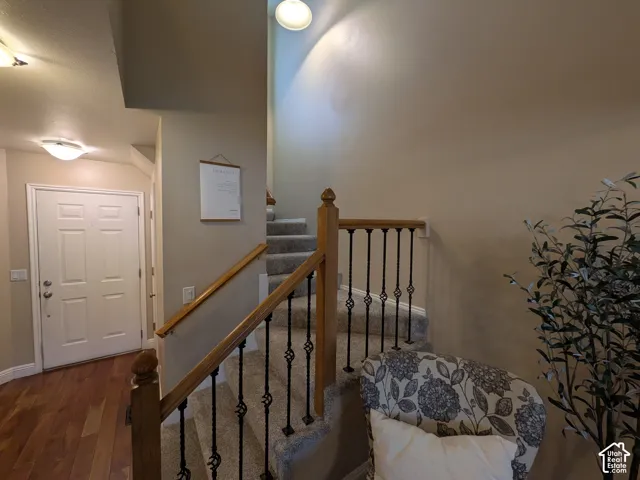Carpeted staircase, wood banister with wrought iron balusters, and flush mount lighting