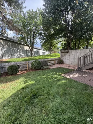 Grassed backyard, wood fencing, and a brick paver patio