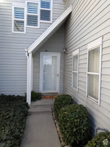 Light gray siding exterior with white window frames and a glass-paneled entry door