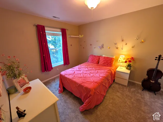 Neutral wall tones, window with vertical blinds, textured carpeting, and ceiling-mounted light fixture