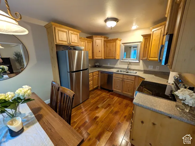 Kitchen featuring hardwood flooring, natural wood cabinetry, stainless steel appliances, and granite-style countertops