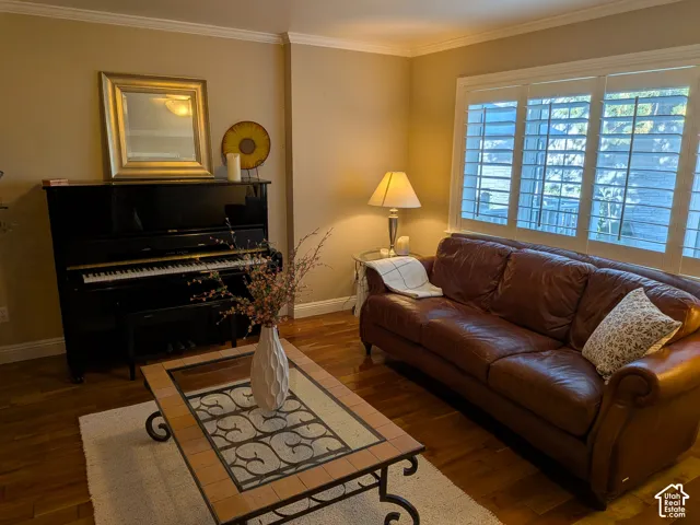 Warm interior featuring hardwood flooring, crown molding, and plantation shutters
