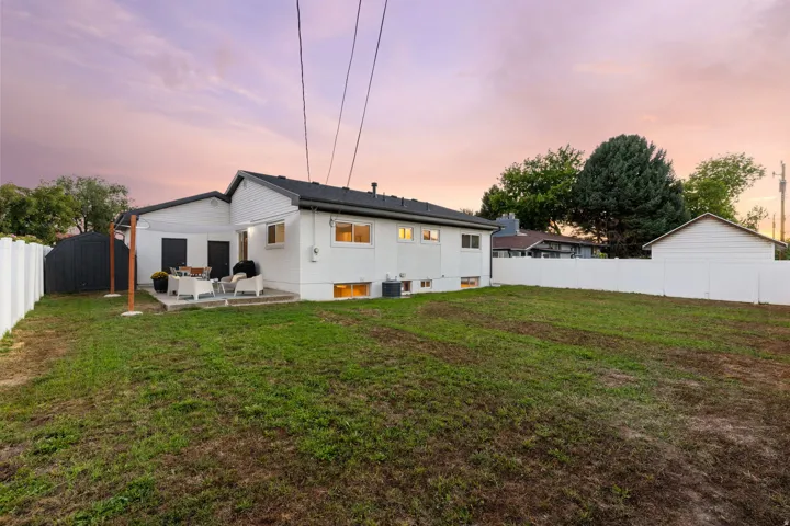 Expansive backyard featuring a concrete patio, privacy fencing, and a detached shed