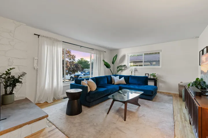 Light wood-finish flooring, white painted walls, and a stone-clad fireplace