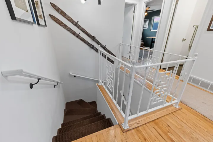 Hardwood flooring, painted white walls, and a decorative white metal railing
