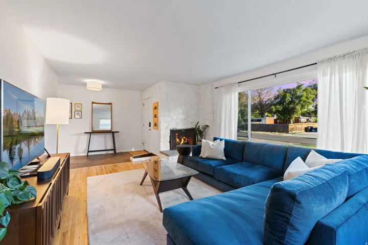 Spacious living area featuring light wood-finish flooring, a stone-clad fireplace, and large sliding glass doors