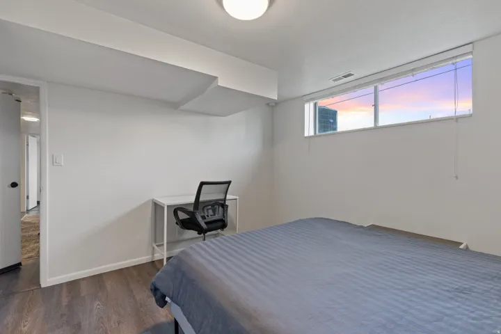 Room featuring wood-finish flooring, a rectangular window with blinds, and recessed lighting