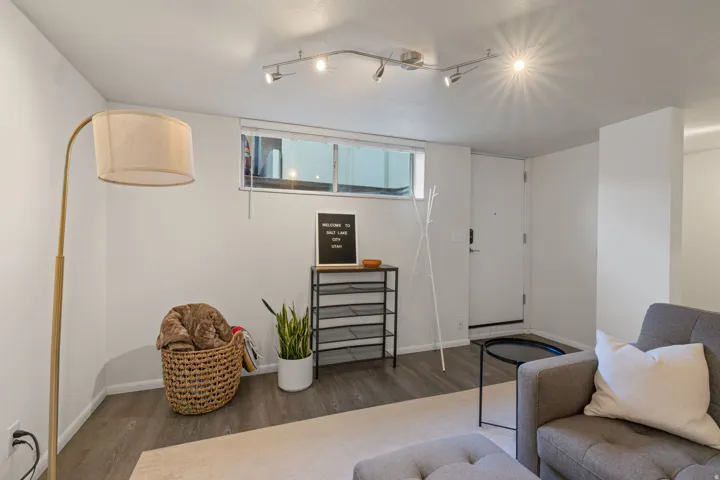 Wood-finish flooring, white walls, track lighting, and a white entry door