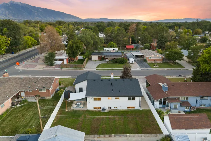 Expansive rear yard with a manicured lawn, white privacy fencing, and a patio area