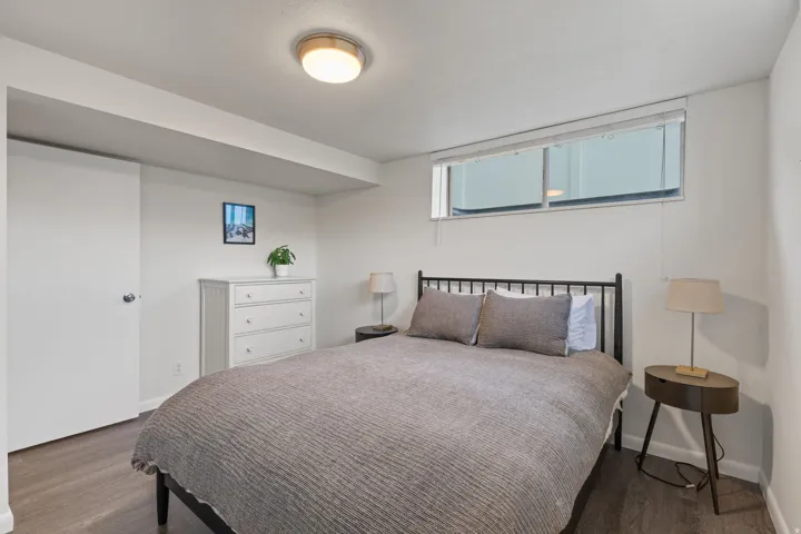 Recessed window, wood-finish flooring, flush mount ceiling light, white painted walls, and a full-size door