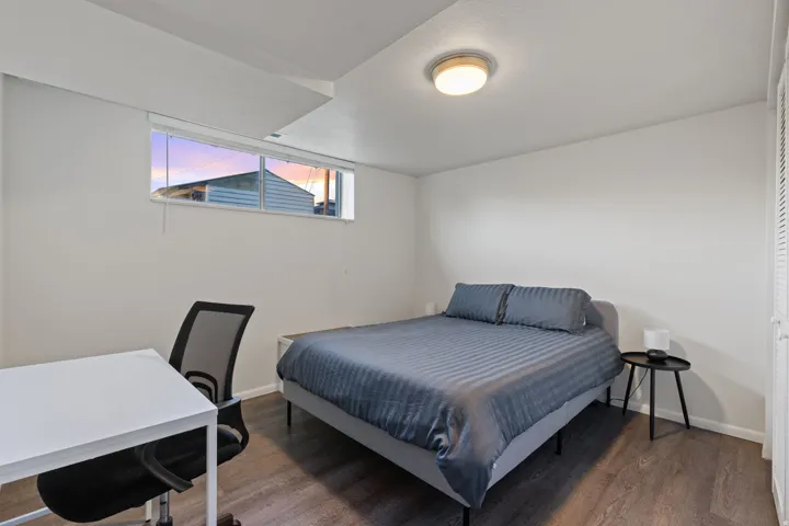 Recessed window with blinds, overhead flush mount lighting, and wood-finish flooring
