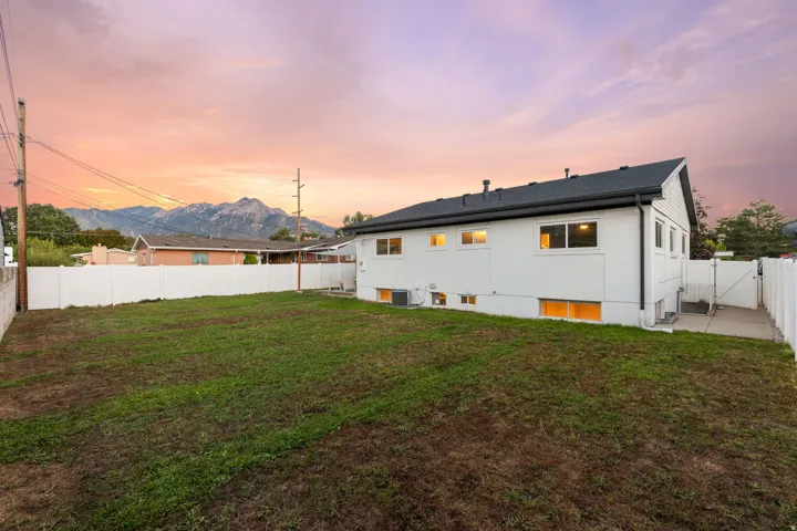 Expansive backyard with a white privacy fence, mountain backdrop, and concrete pathway