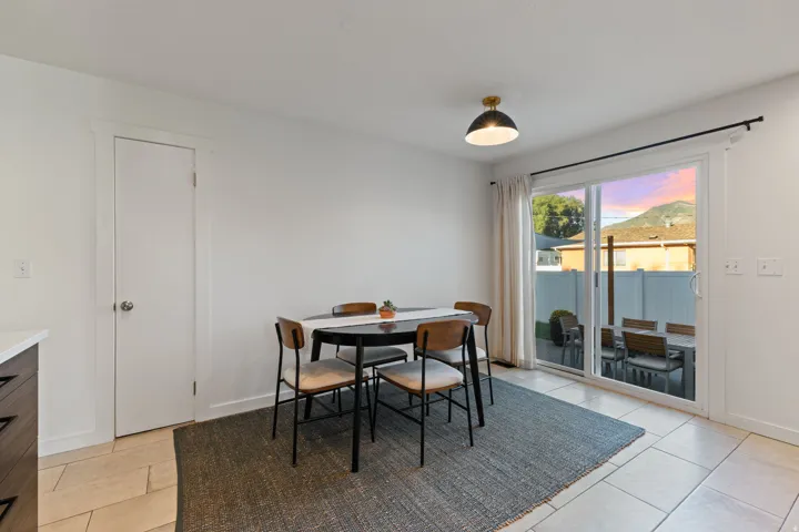 Sliding glass door access to the exterior patio, tile flooring, modern flush mount light fixture, mountain scenery, and white walls