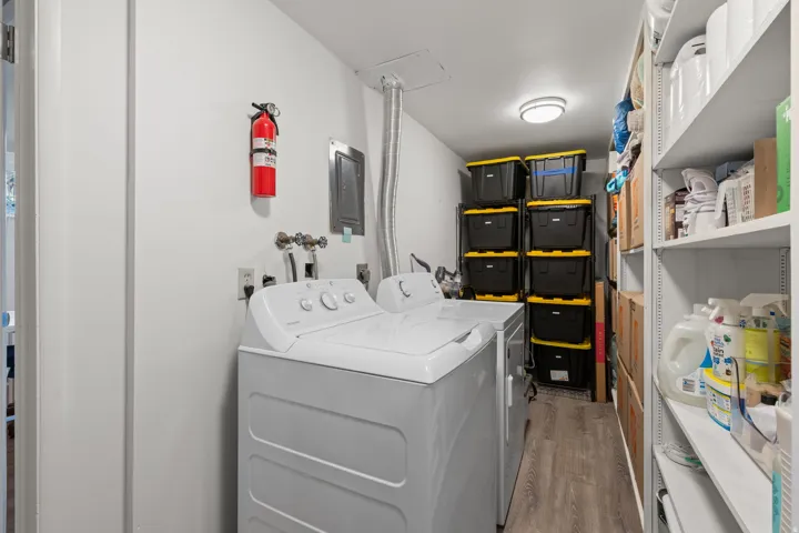 Dedicated laundry area with wood-finish flooring, overhead lighting, and built-in shelving