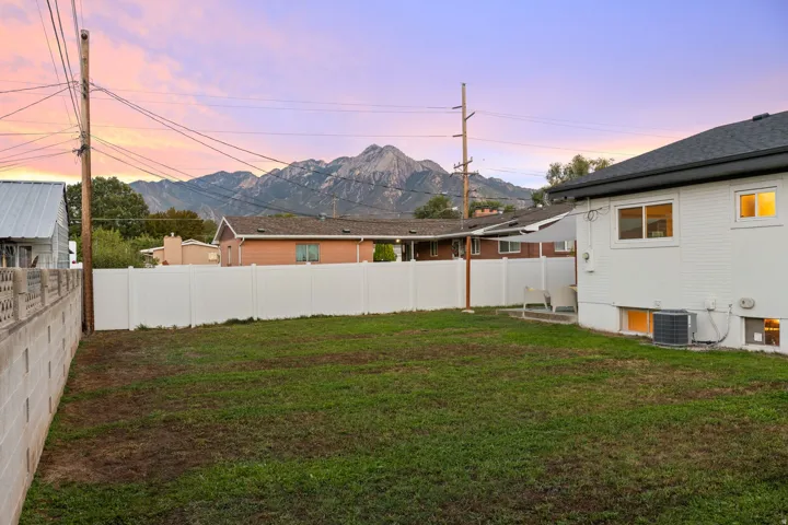Expansive grassy area with a white privacy fence and concrete block wall