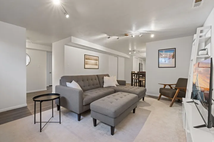 Recessed lighting illuminates the living area with light wood-finish flooring