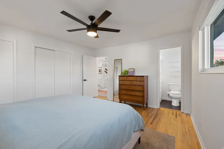 Wood-finish flooring, white walls, black ceiling fan with integrated lighting, and multiple windows