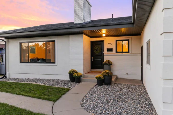 Exterior featuring a white brick chimney, dark soffits, black-framed windows, and a black entry door