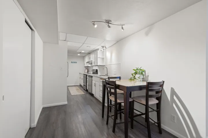 Galley kitchen with white cabinetry, subway tile backsplash, and stainless steel appliances