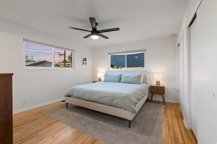 Hardwood flooring, white walls, two windows, and dual closet doors