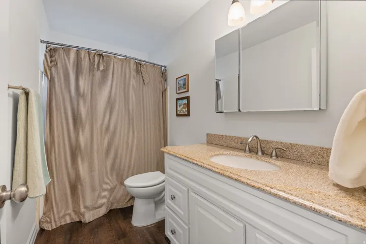 White vanity with recessed panel cabinet doors, an undermount sink, and a speckled countertop