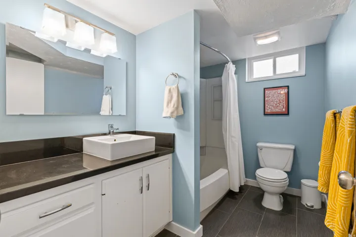 Vanity with a rectangular vessel sink, dark countertop, and white cabinetry