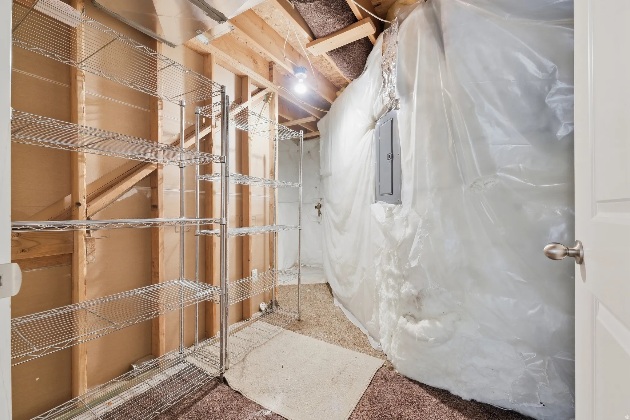Unfinished interior space with exposed wood framing, an electrical panel, and a partially finished floor
