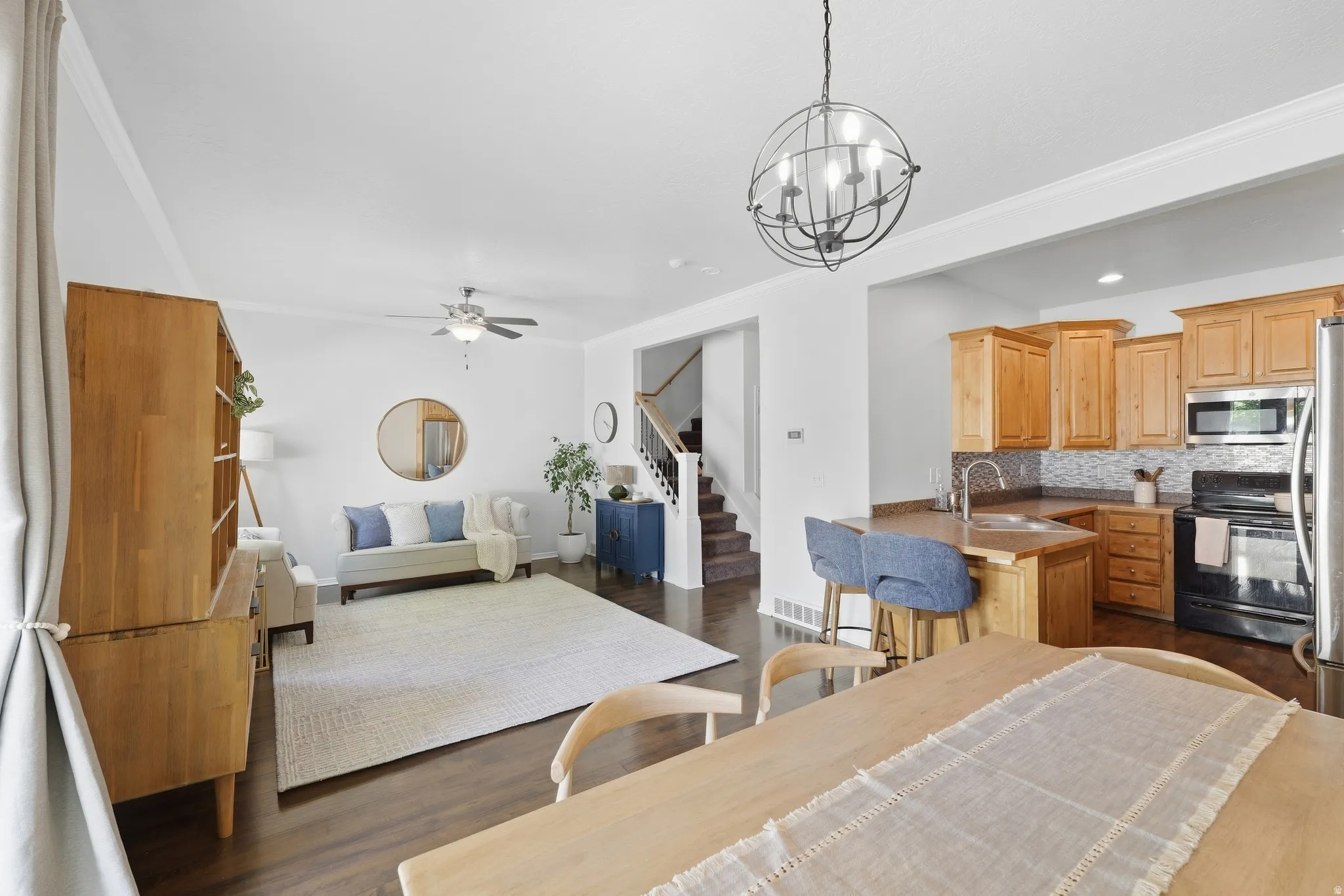 Open concept living area with wood-finish flooring, kitchen island with built-in sink, and stainless steel appliances