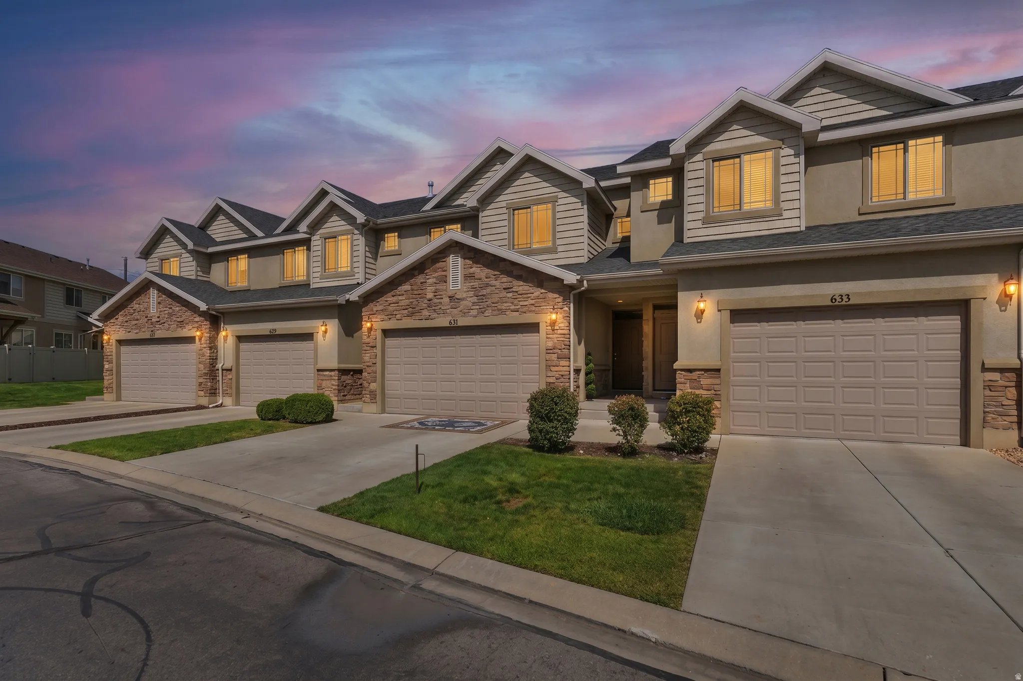 Multi-level townhome featuring stone and siding exterior, concrete driveways, and a two-car garage