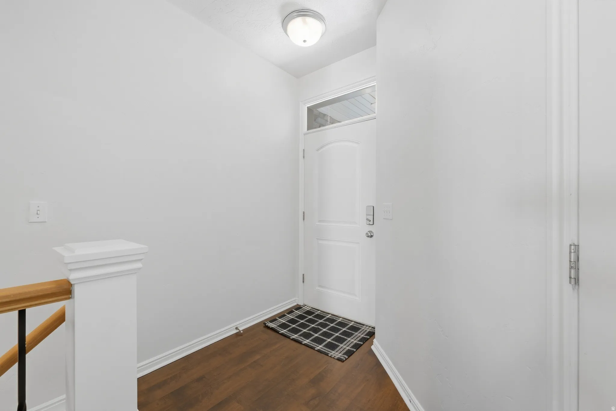 Entryway featuring wood-finish flooring, white walls, and a transom window above the entrance door