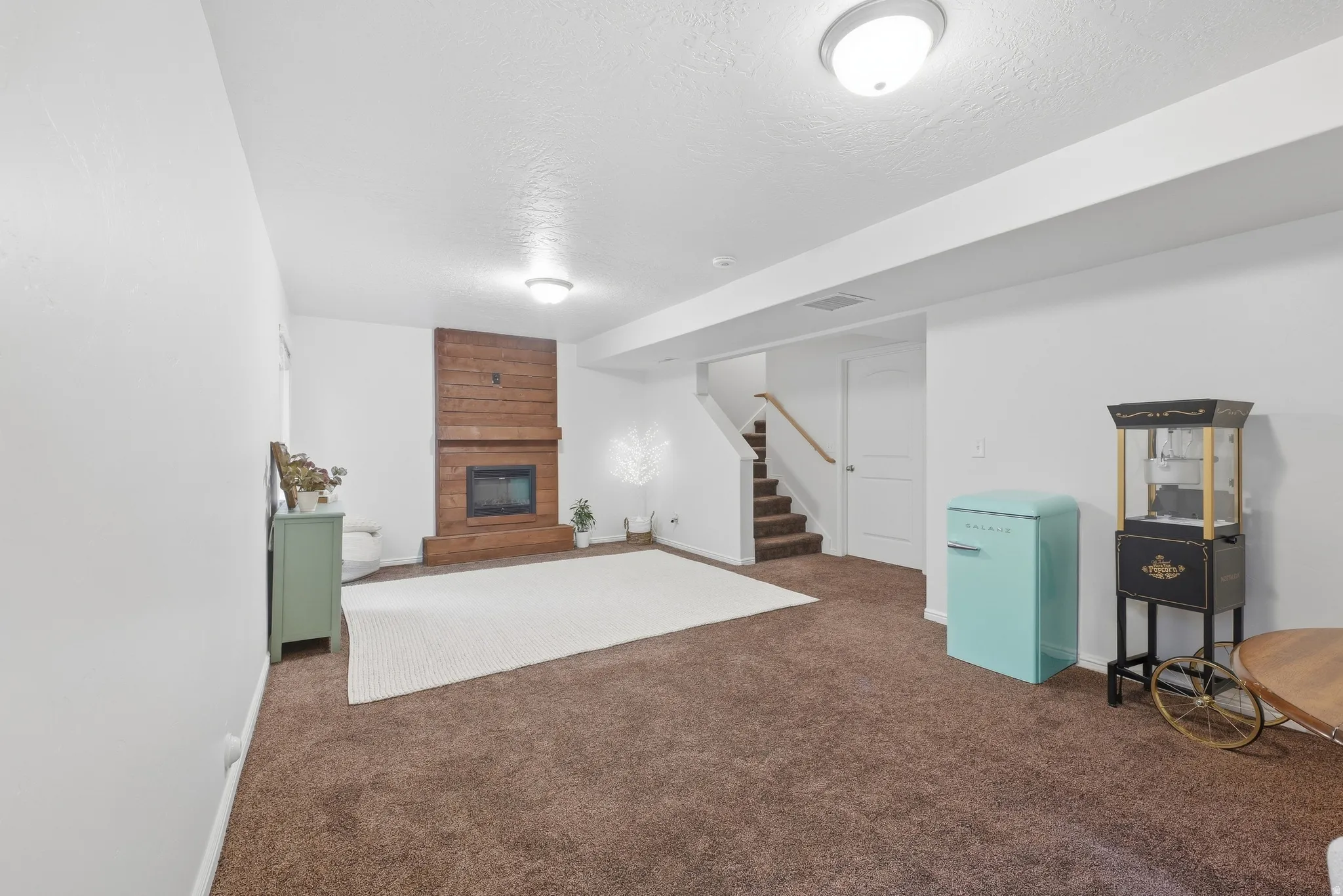 Spacious room featuring a brick-clad fireplace with a wood-panel accent wall, recessed lighting, and carpeted flooring